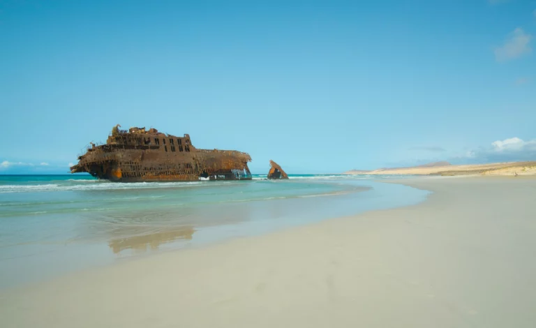 Naufrágio do navio Cabo Santa Maria encalhado na praia da Ilha da Boavista, em Cabo Verde, com areia clara, mar calmo e céu azul num cenário icónico e isolado do arquipélago.