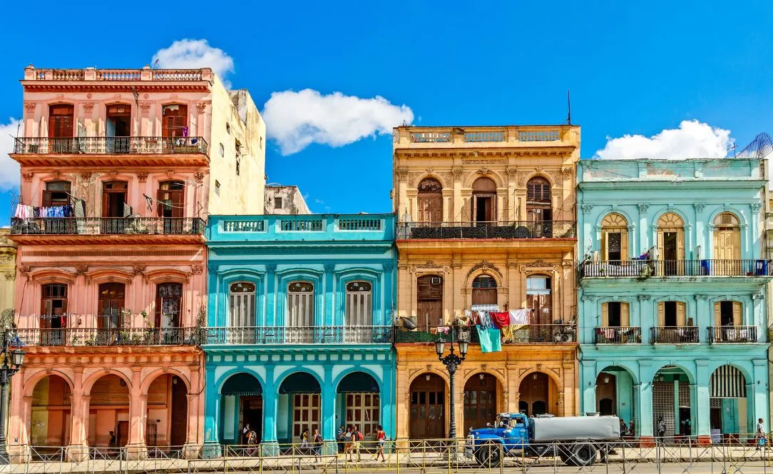 Edifícios coloniais coloridos nas ruas de Havana, Cuba, com fachadas em tons pastel, varandas tradicionais e roupa estendida, representando o charme histórico e vibrante da cidade.