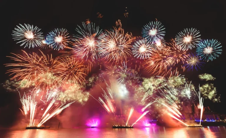 Espetáculo de fogos de artifício multicoloridos refletidos no mar durante uma grande celebração noturna na orla de Salvador, Bahia.