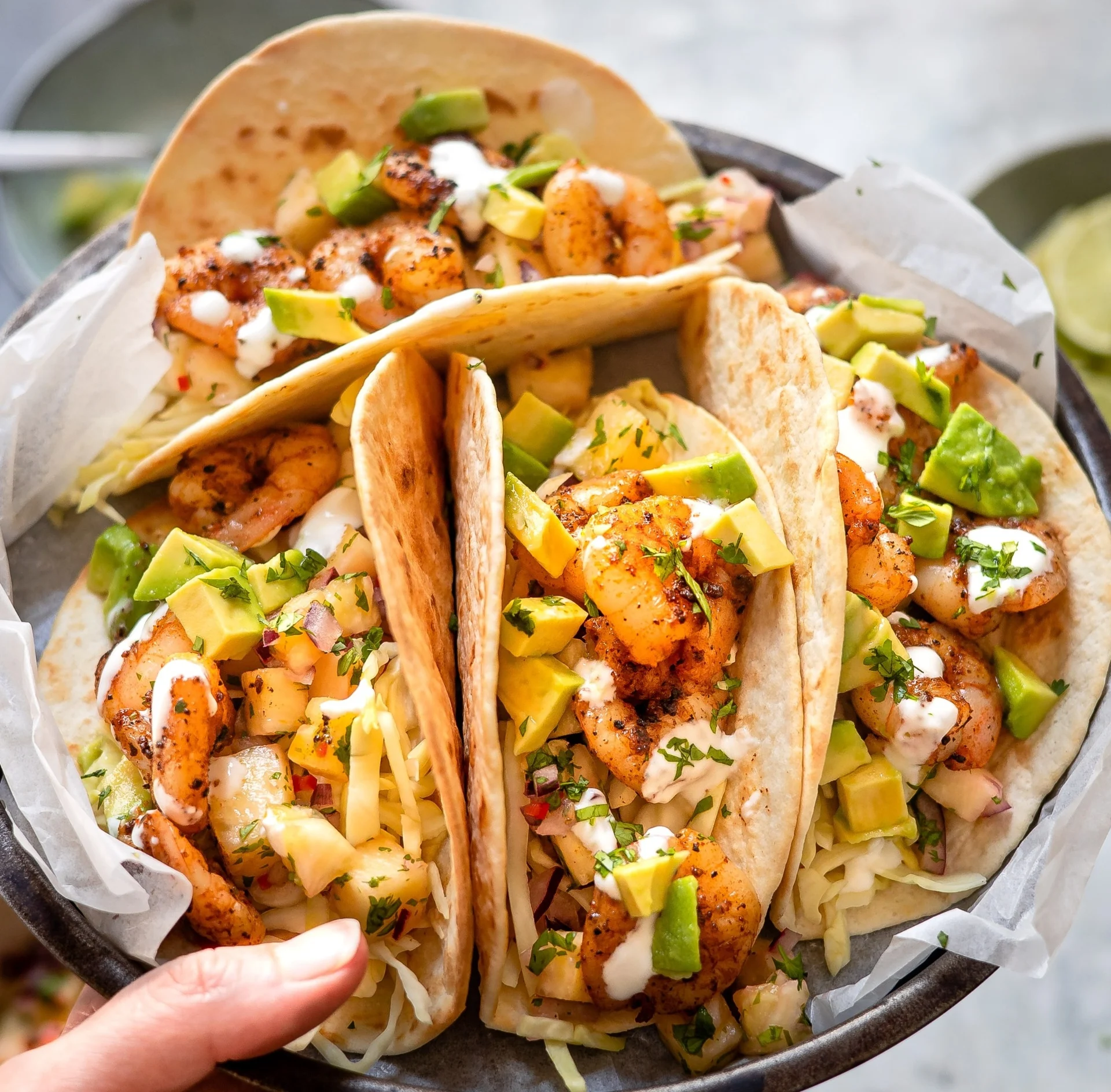 Prato de tacos mexicanos recheados com camarão grelhado, abacate, legumes frescos e molho cremoso.